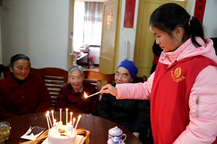 午饭后，孙建华老师拿出了生日蛋糕，而周雪琴则悉心地将蜡烛插上并点燃。